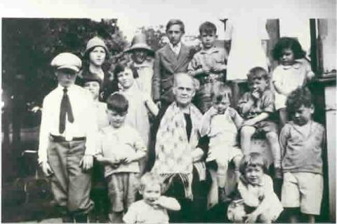 Senior women seated and surrounded by 15 children, circa 1921