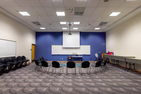 Small group of chairs facing projector screen and white board in Multipurpose Room L107 