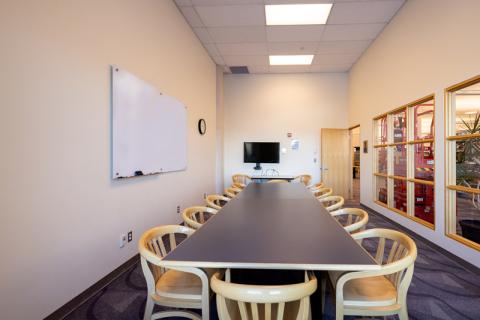 Long rectangular table with chairs, TV and whiteboard in conference room L167