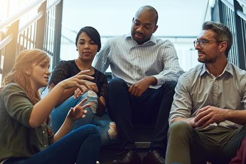 Diverse group of adults sitting on stairs and having a conversation.