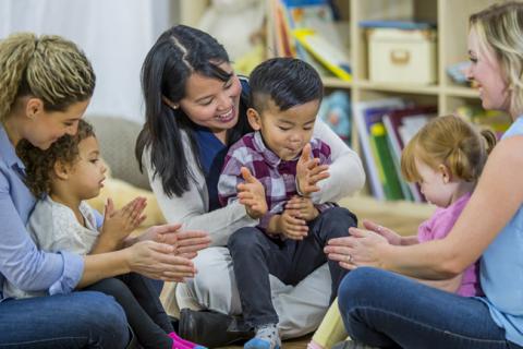 Three women and three children clapping.