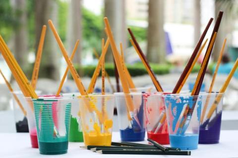 Plastic cups holding paint and paint brushes.