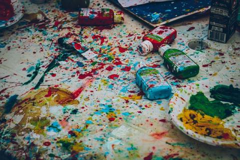 A mess of glitter and paint over art supplies on a flat surface.