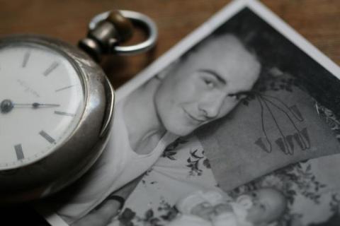 Old watch beside a black and white photo of a new father.