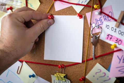 Hand placing paper on an evidence board.