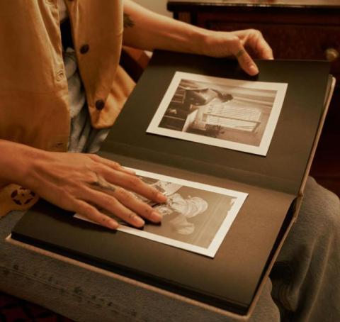 Adult holding an old family album on their lap.