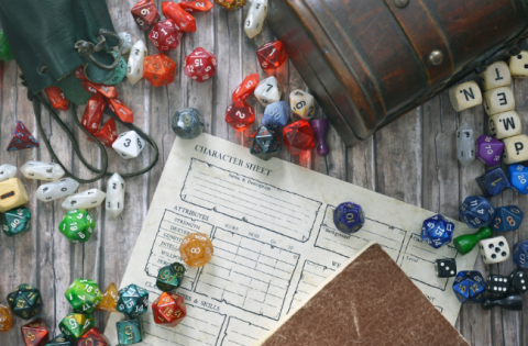 RPG dice spilling from leather containers over character sheet on table.