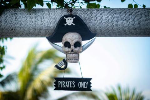 A sign that says 'Pirates Only' underneath and skull and cross bones wearing a pirate hat.