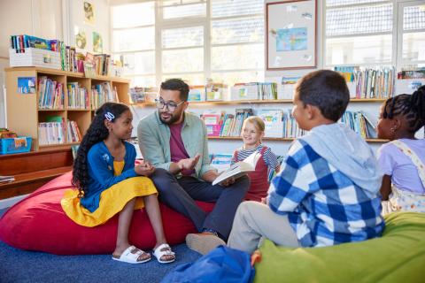Male teacher reading books to students