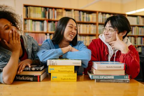 Teenagers laughing and talking together in a library. 
