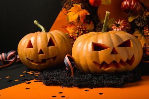 Two Carved pumpkins sitting in fall decor
