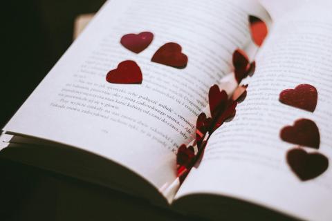 open book with red heart-shaped confetti 