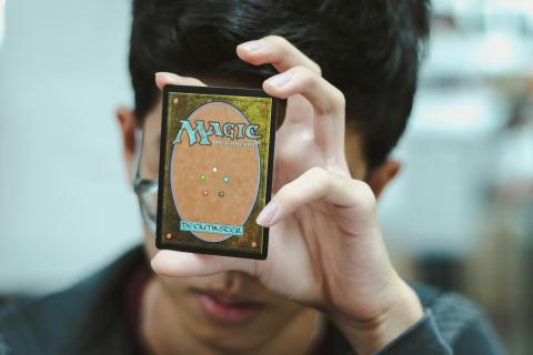 Teen boy holding Magic: The Gathering trading card. 
