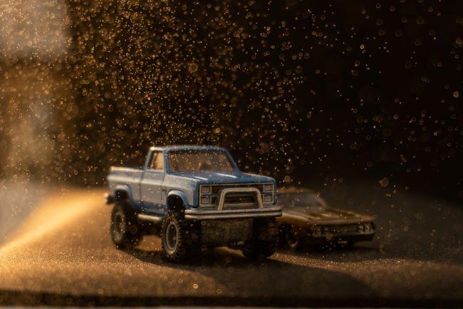 Rendering of blue truck with big tires and muscle car racing.