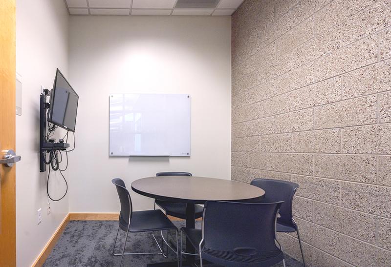 Small table with chairs, glass whiteboard, TV and Blu-ray player.