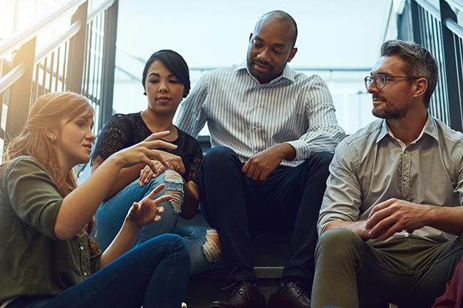 Diverse group of adult sitting on stairs and having a conversation.