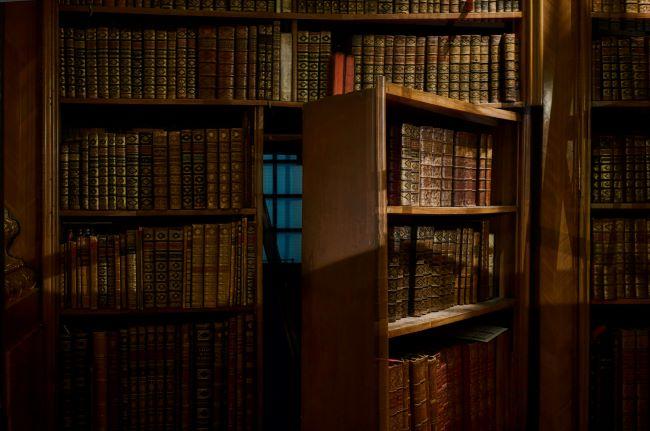 Hidden room seen behind open bookcase.