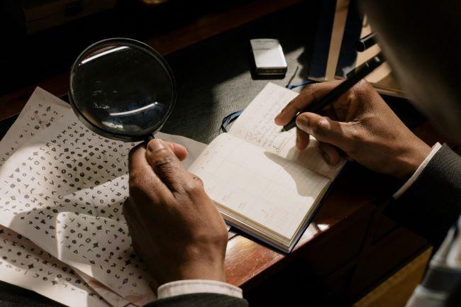 Adult hands writing out a code in a diary.