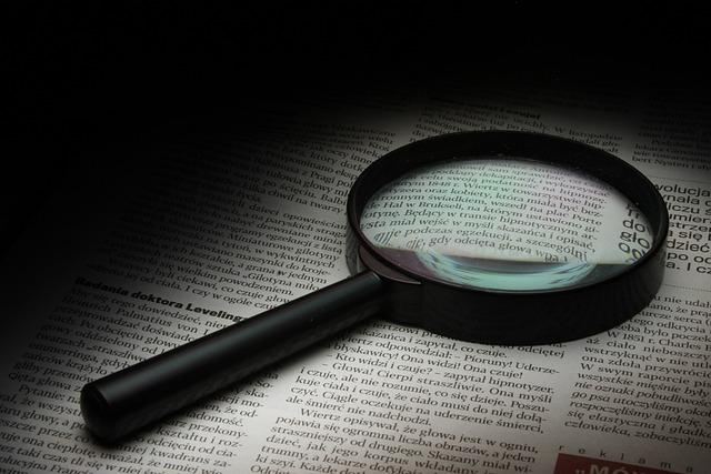 Magnifying glass atop old newspaper.