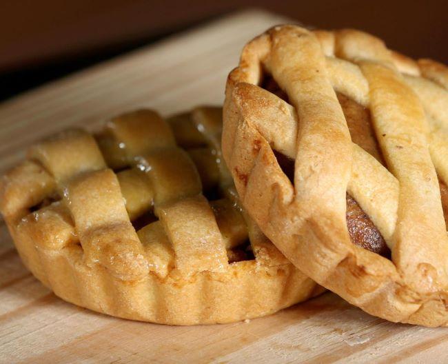 Two small pies on a cutting board with one leaning on the other.