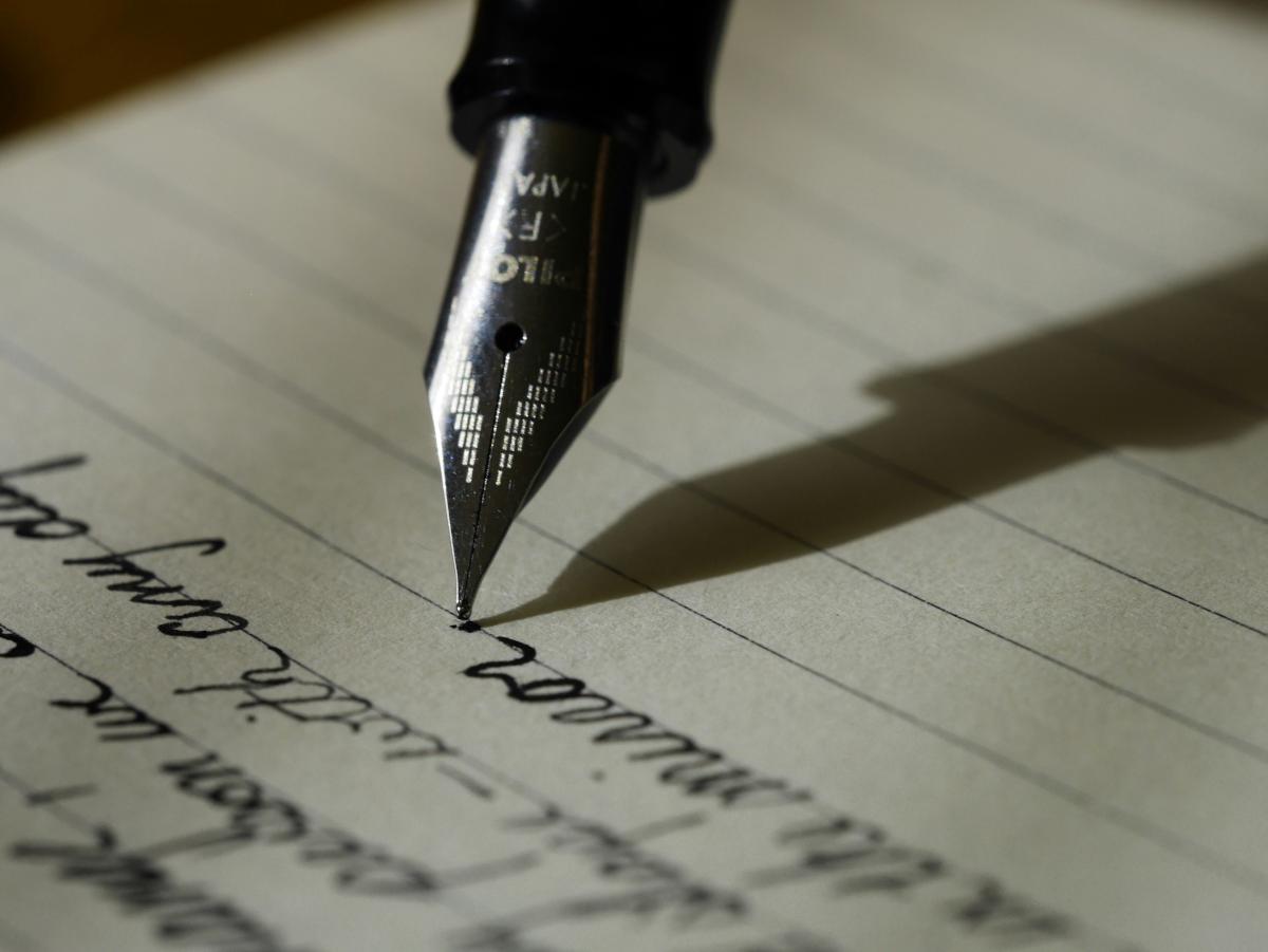 Fountain pen writing cursive on lined paper.