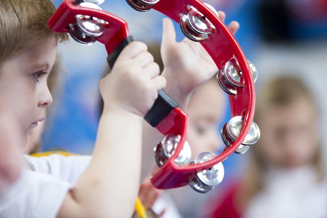 Young boy shaking a tambourine.