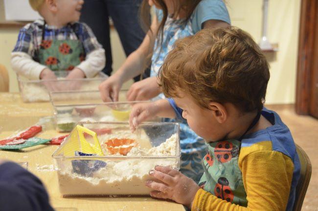 Young children playing with toys in flour.