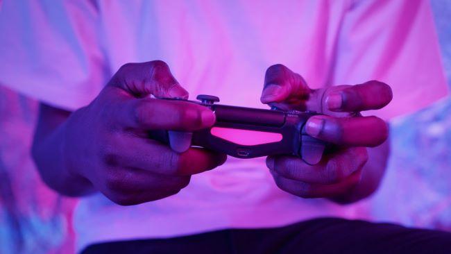 Hands holding a game controller with purple lighting.