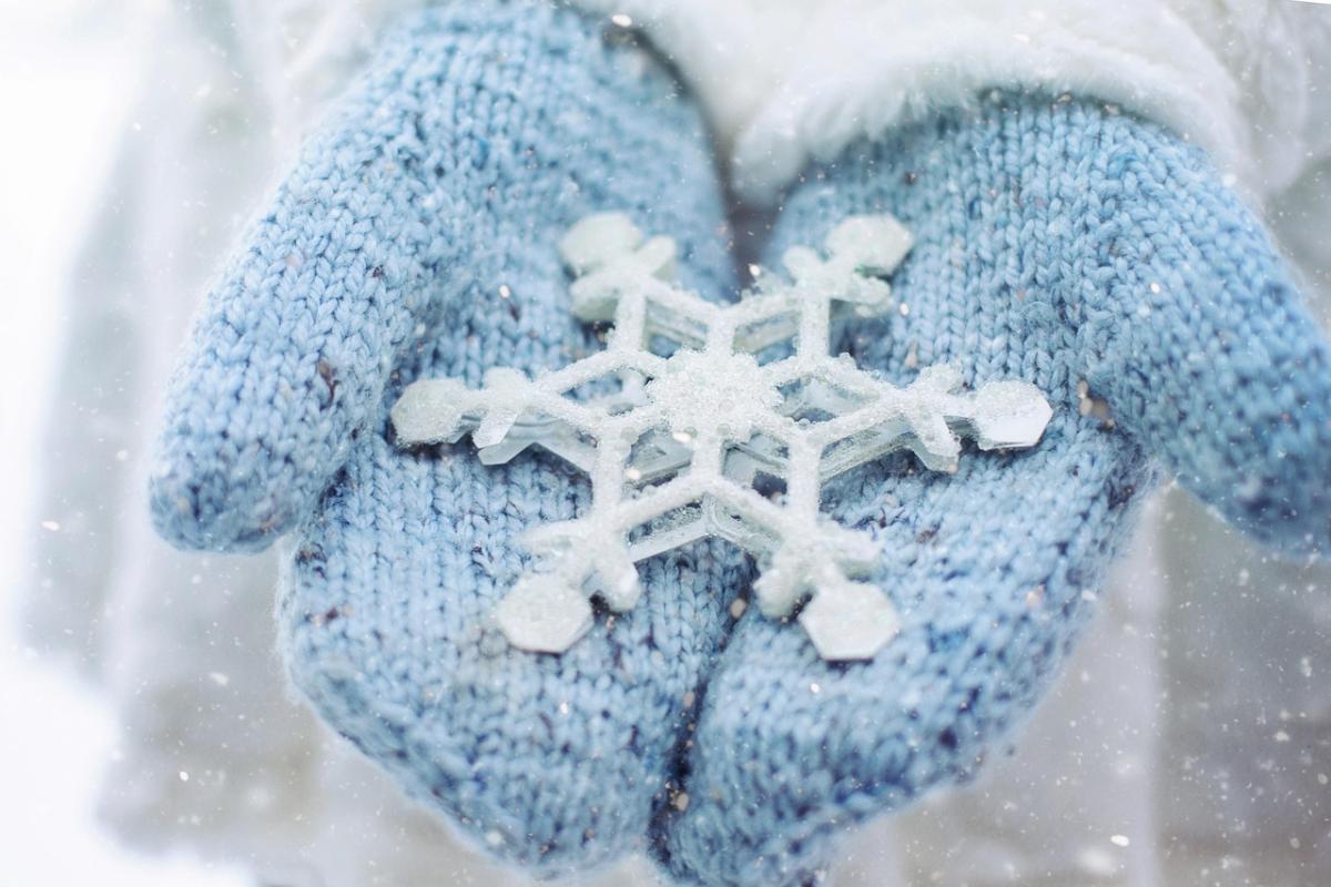 Light blue mittens holding a large snowflake